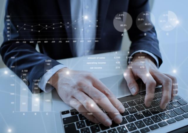 キーボードを操作するビジネスマンと透過グラフ