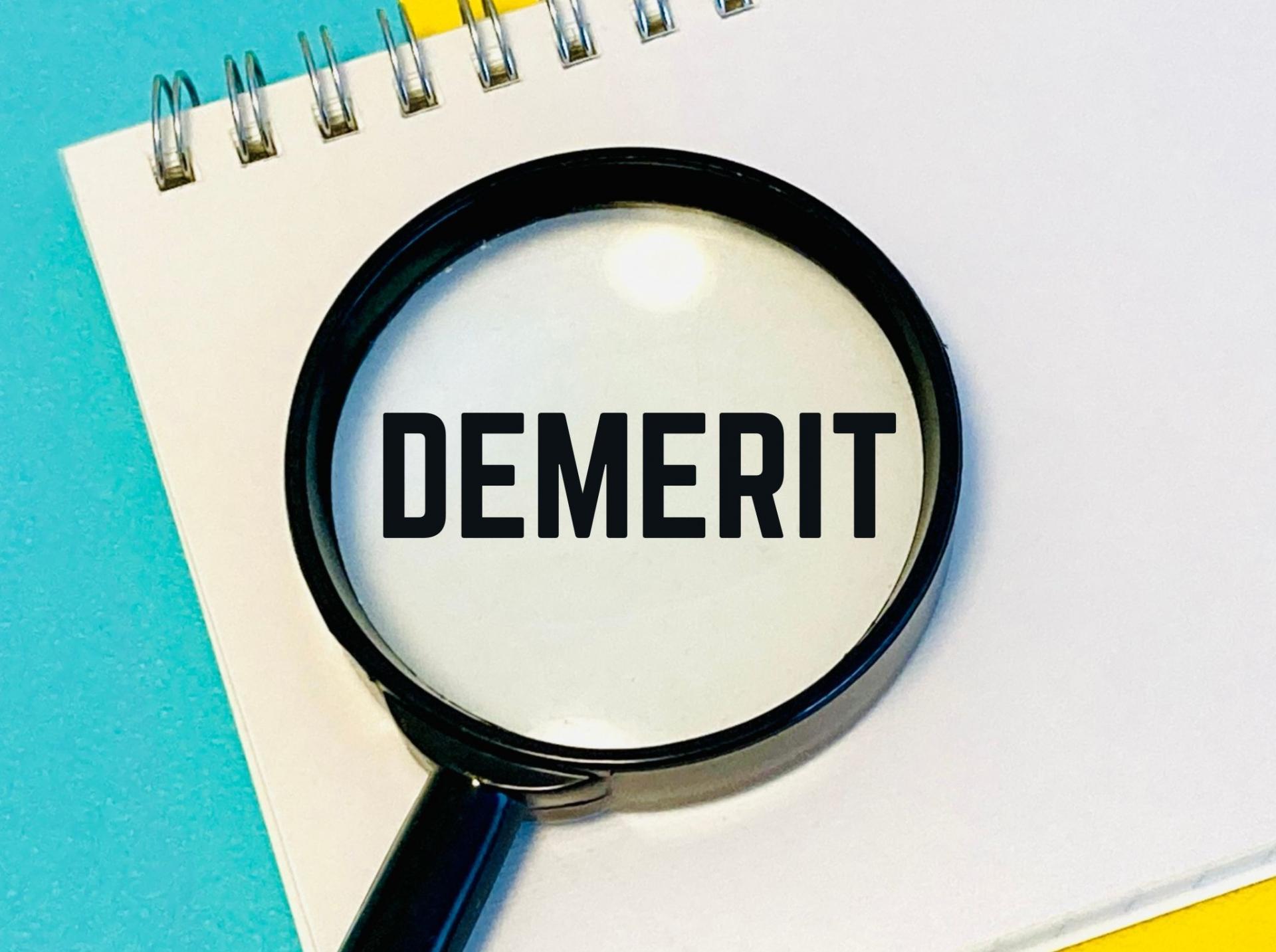 DEMERITと書かれたノートとルーペ